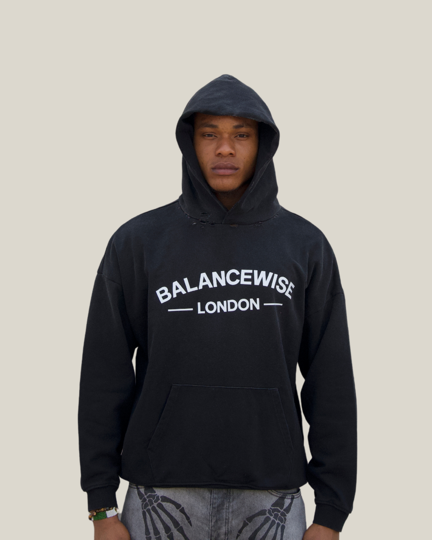 Person wearing a black hoodie with 'Balancewise London' text on a beige background