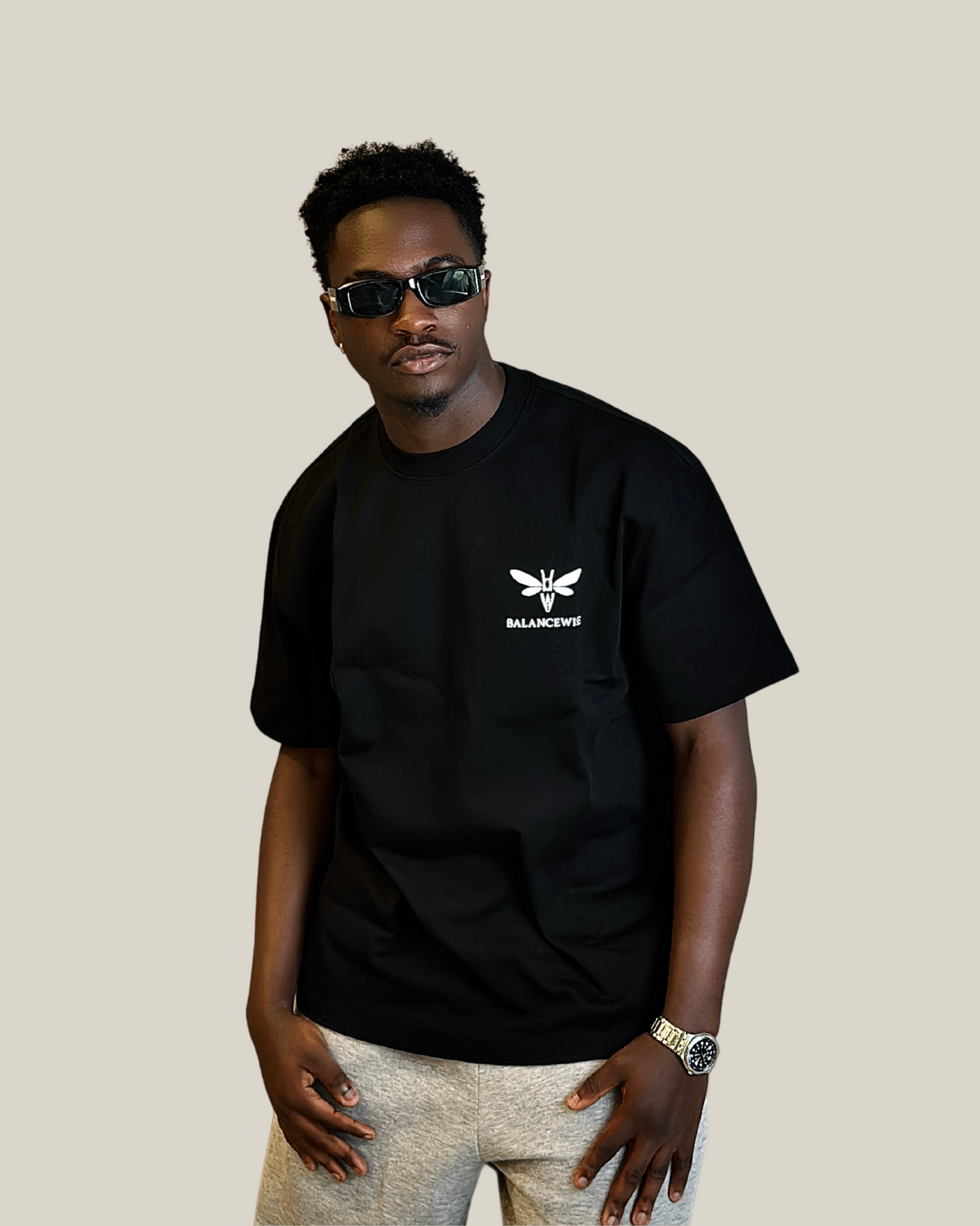 Man wearing Liam black t-shirt with a logo on a beige background