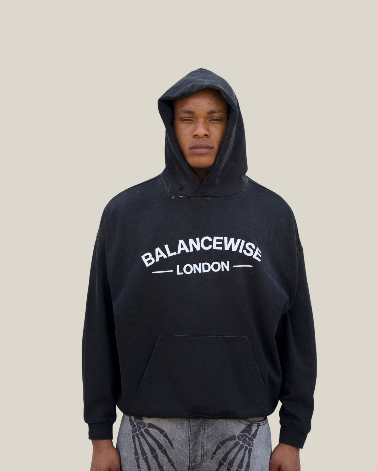 Person wearing a black hoodie with 'Balancewise London' text on a beige background