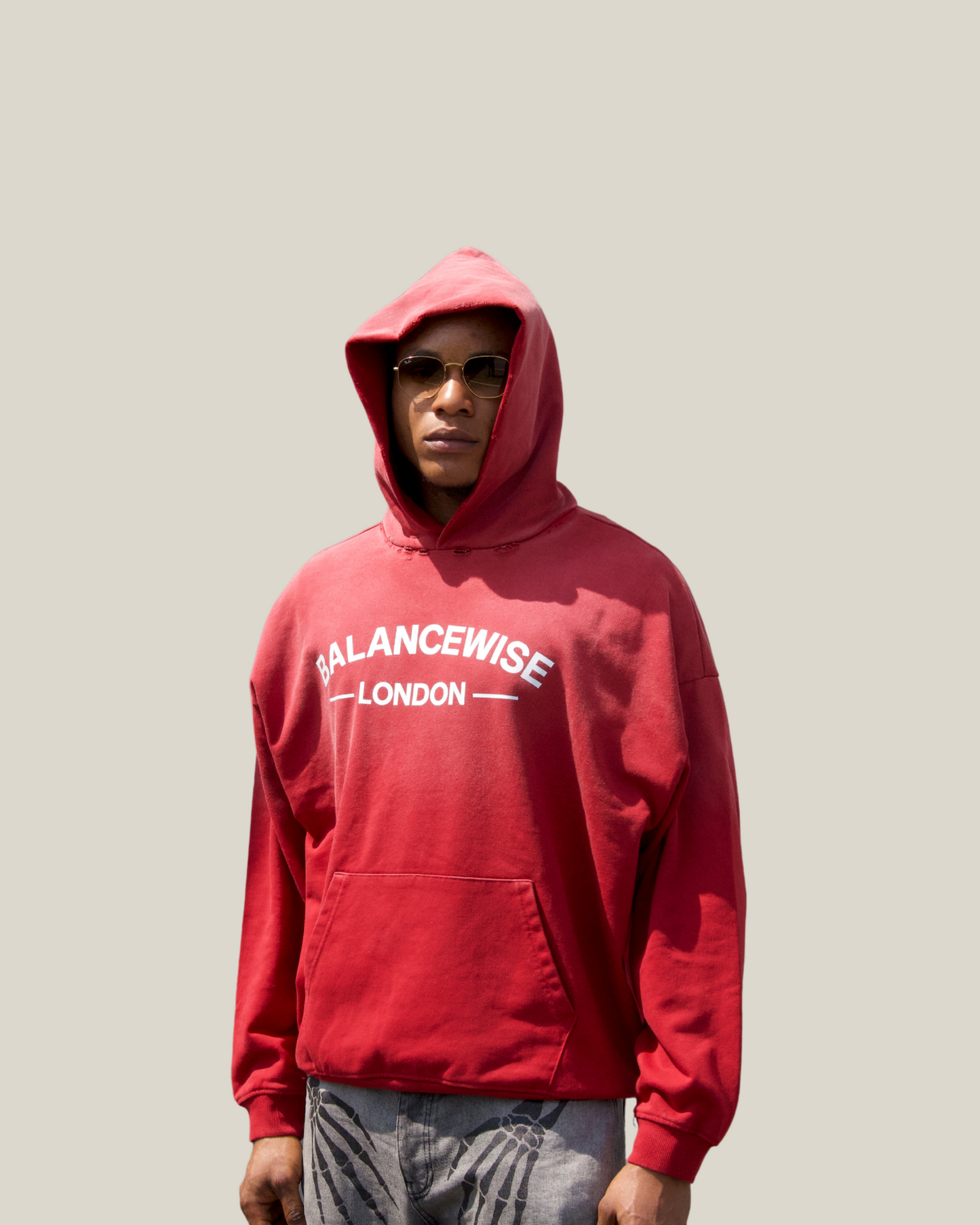 Person wearing a navy blue hoodie with 'Balancewise London' text on a red background front