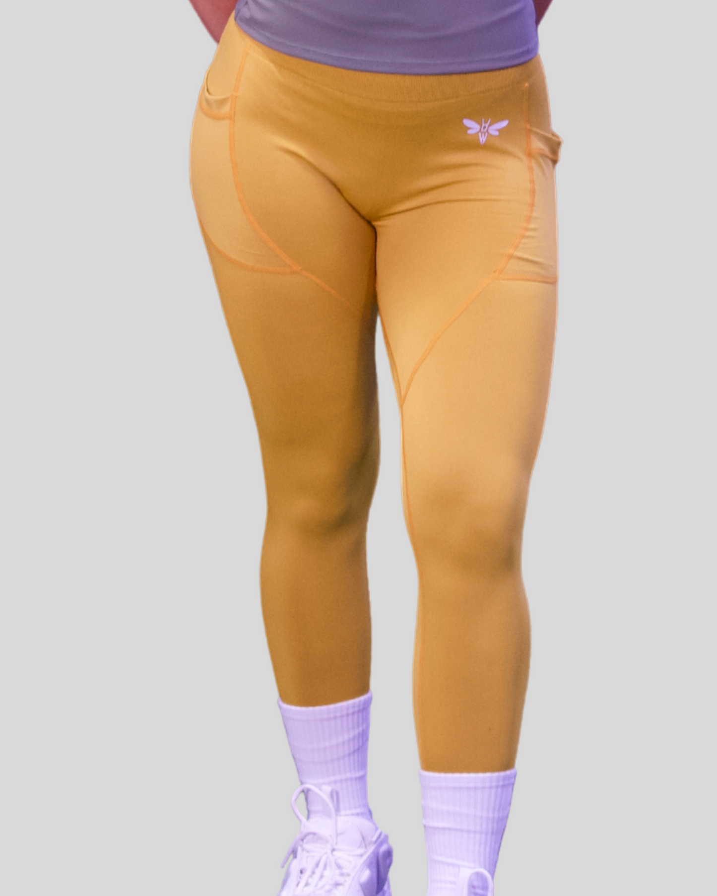 Person wearing mustard yellow balancewise leggings with a logo on