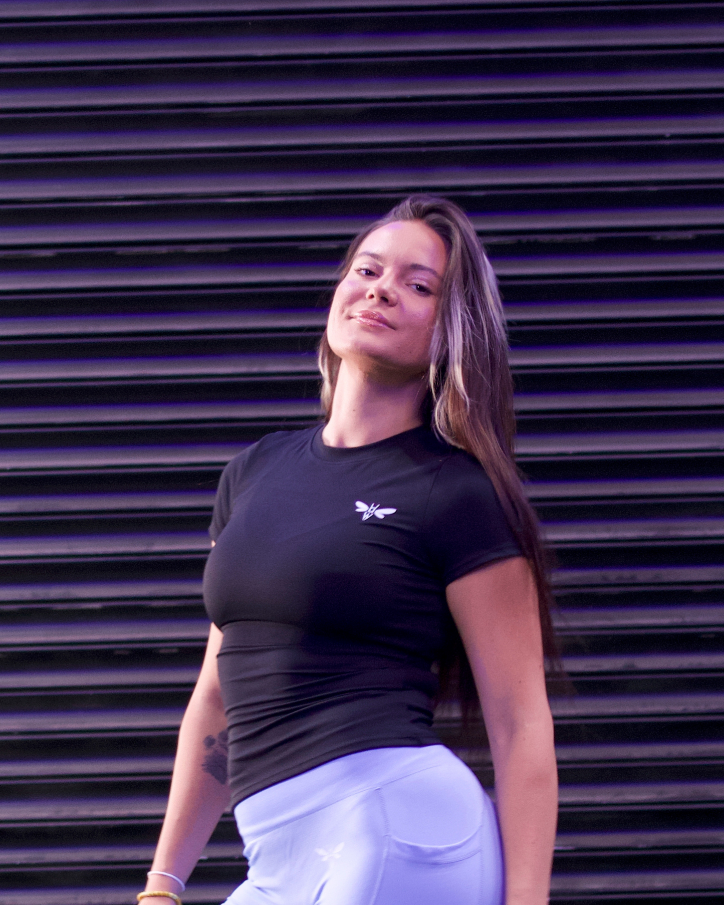 Woman wearing a Balancewise Balance Black compression tee, arm raised during gym workout
