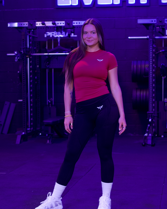 Female athlete in red Balancewise activewear top lifting her arm in a fitness studio
