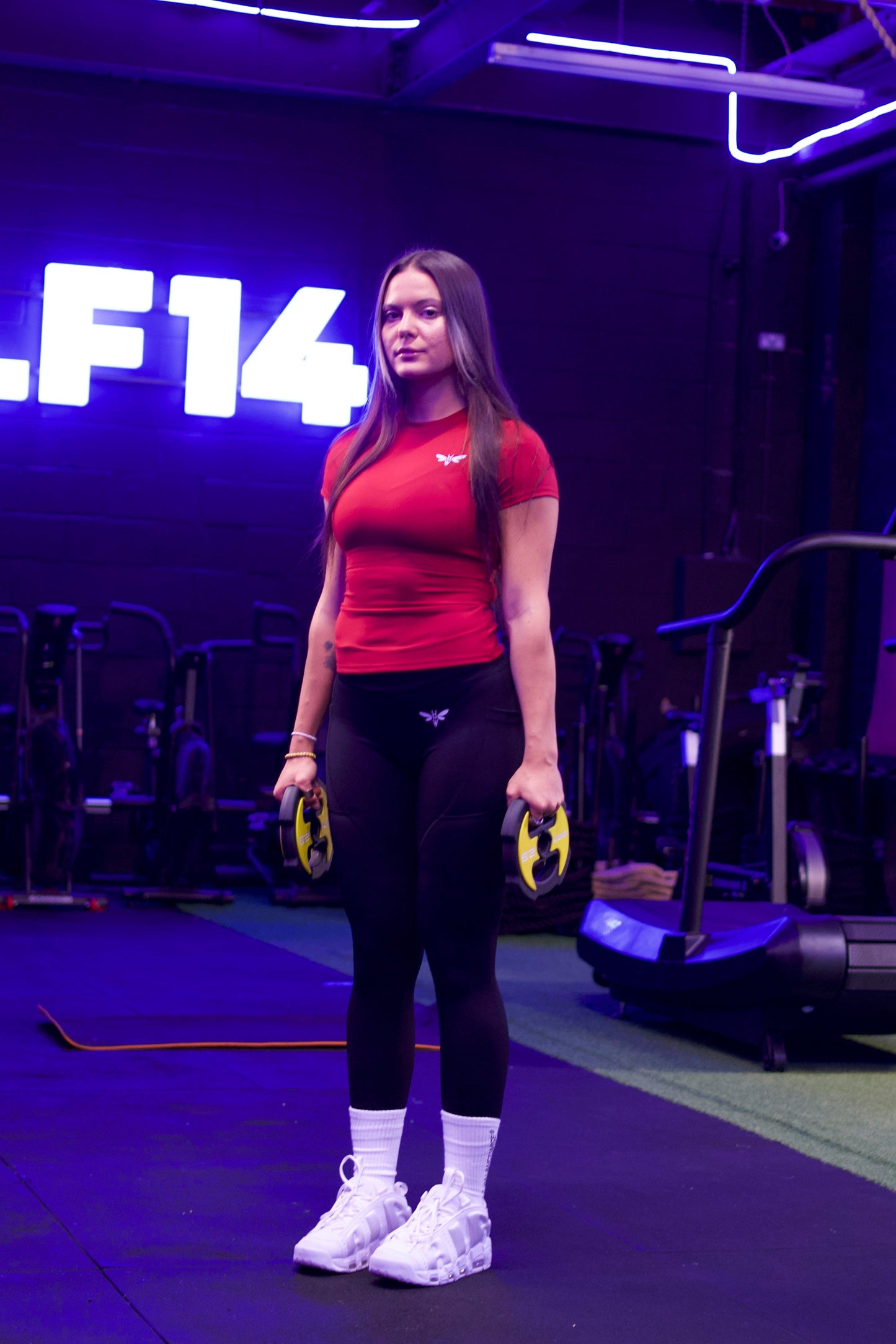 Woman flexing her arm in a red Balancewise gym shirt with visible logo