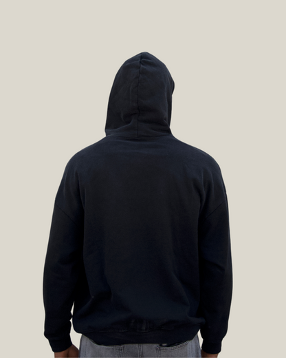 Person wearing a black hoodie from behind on a beige background